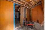 This image showcases a room undergoing renovation, highlighting exposed wooden beams, insulation, and unfinished walls, suggesting a potential fixer-upper opportunity.