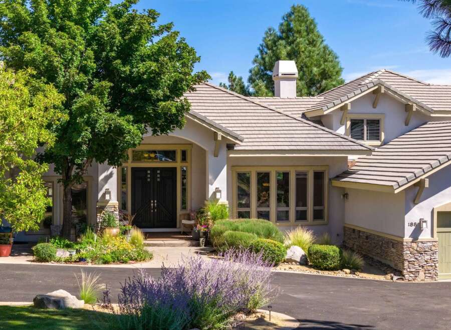 Discover this stunning home featuring a grand double-door entrance and a beautifully landscaped front yard with vibrant flowers and lush greenery.