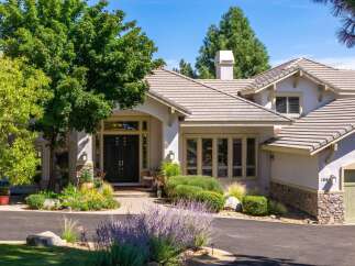 Discover this stunning home featuring a grand double-door entrance and a beautifully landscaped front yard with vibrant flowers and lush greenery.