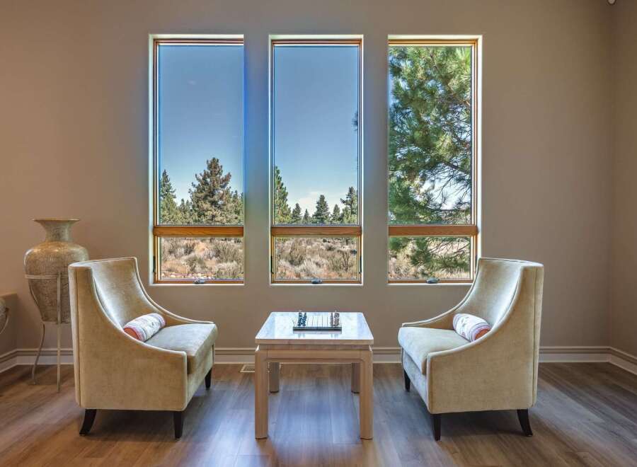 Experience breathtaking views from this stunning living space, featuring three large windows that frame the picturesque landscape.