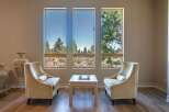 Experience breathtaking views from this stunning living space, featuring three large windows that frame the picturesque landscape.