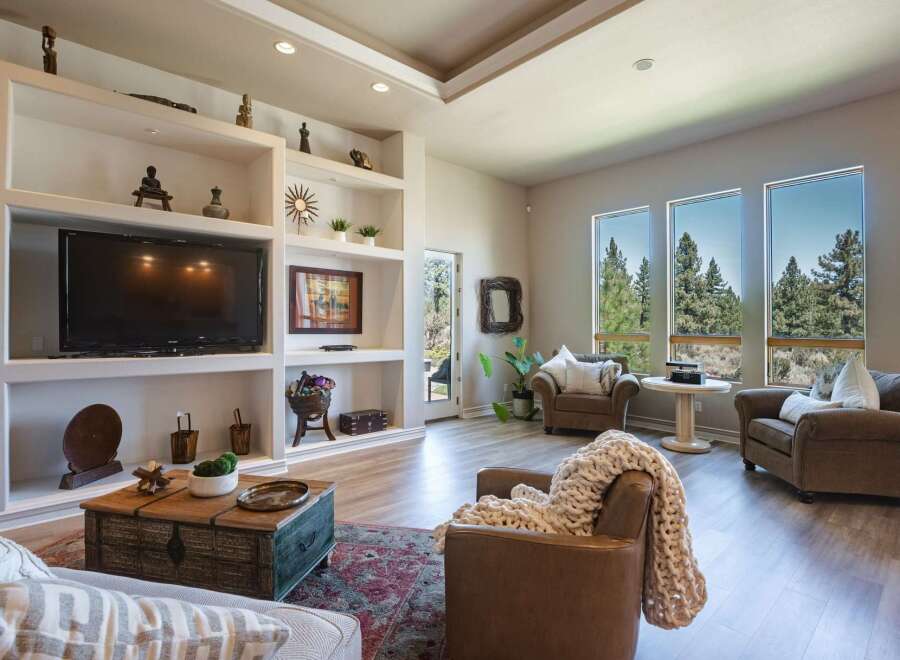 Experience breathtaking panoramic views from this stunning living room, featuring expansive windows that showcase a lush forest landscape.