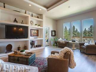 Experience breathtaking panoramic views from this stunning living room, featuring expansive windows that showcase a lush forest landscape.
