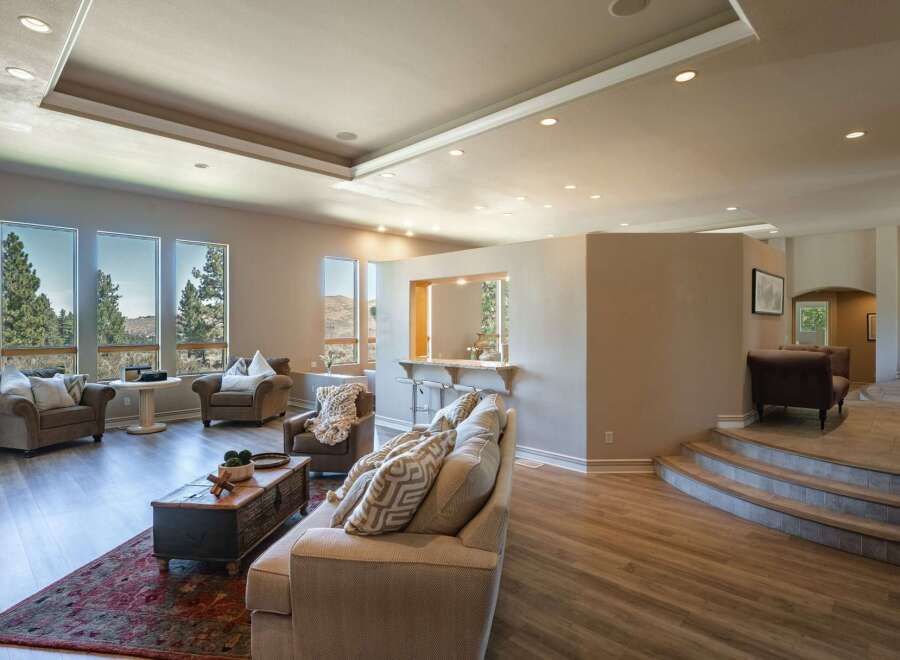 Experience luxury living in this expansive open-concept home, featuring a sunken living area with a cozy fireplace and large windows offering breathtaking mountain views.