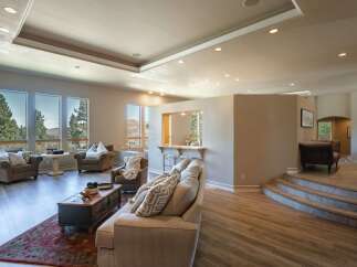 Experience luxury living in this expansive open-concept home, featuring a sunken living area with a cozy fireplace and large windows offering breathtaking mountain views.