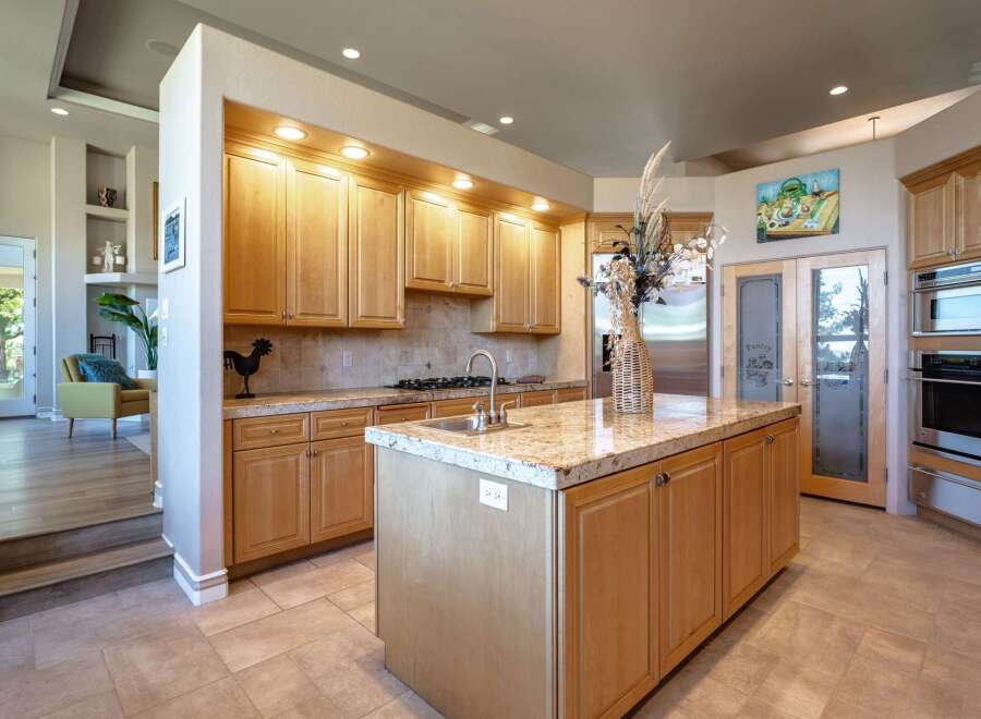 This spacious kitchen features light wood cabinetry and granite countertops, offering ample storage and workspace.