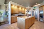 This spacious kitchen features light wood cabinetry and granite countertops, offering ample storage and workspace.