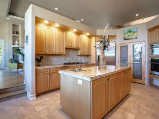 This spacious kitchen features light wood cabinetry and granite countertops, offering ample storage and workspace.