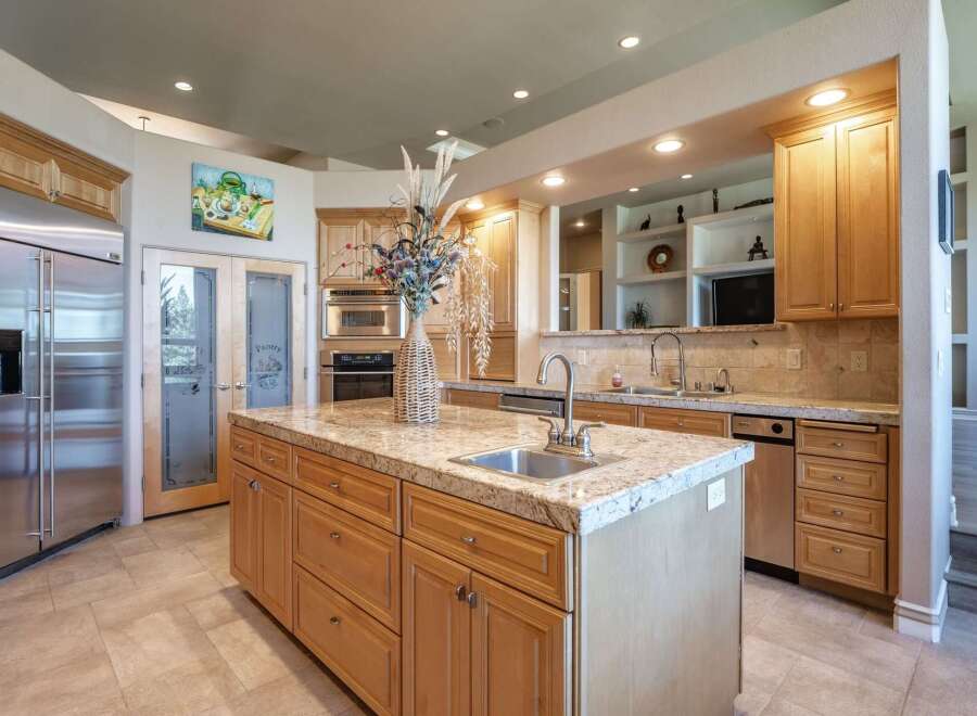 Experience luxury in this spacious kitchen featuring a large granite island with a built-in sink, perfect for meal prep and entertaining.