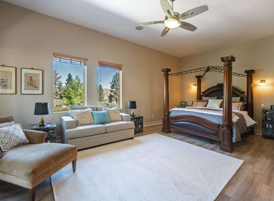 Experience luxury in this spacious master suite featuring a grand four-poster bed and a comfortable seating area.