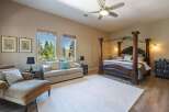 Experience luxury in this spacious master suite featuring a grand four-poster bed and a comfortable seating area.