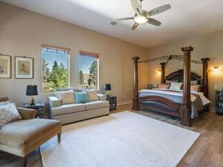 Experience luxury in this spacious master suite featuring a grand four-poster bed and a comfortable seating area.