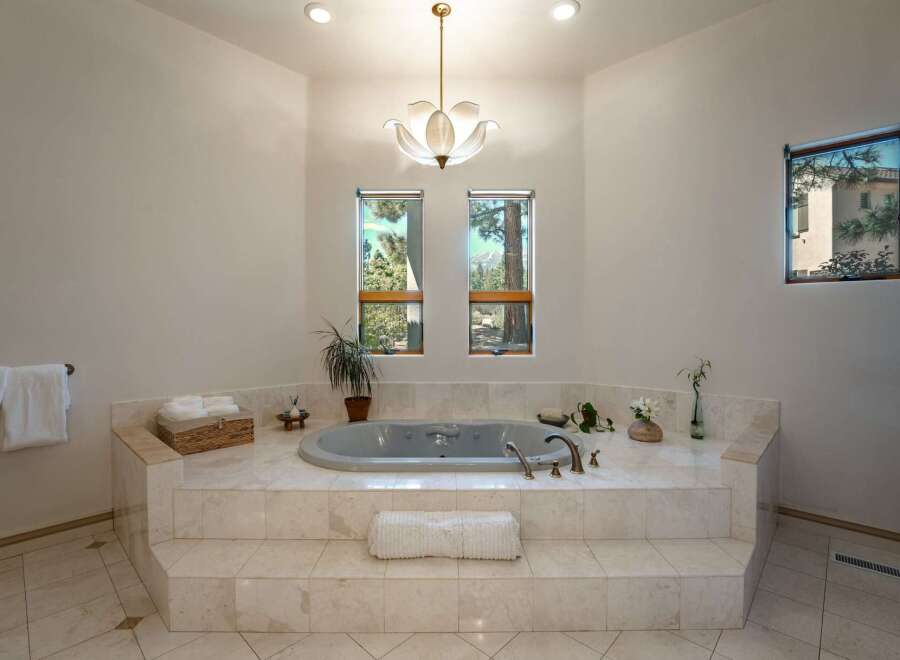 Indulge in luxury in this stunning bathroom featuring a spacious jetted tub set on a marble-clad platform.