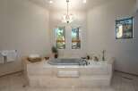 Indulge in luxury in this stunning bathroom featuring a spacious jetted tub set on a marble-clad platform.