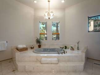 Indulge in luxury in this stunning bathroom featuring a spacious jetted tub set on a marble-clad platform.