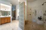 Experience luxury in this spacious master bathroom, featuring a stunning walk-in shower enclosed by a curved glass block wall.