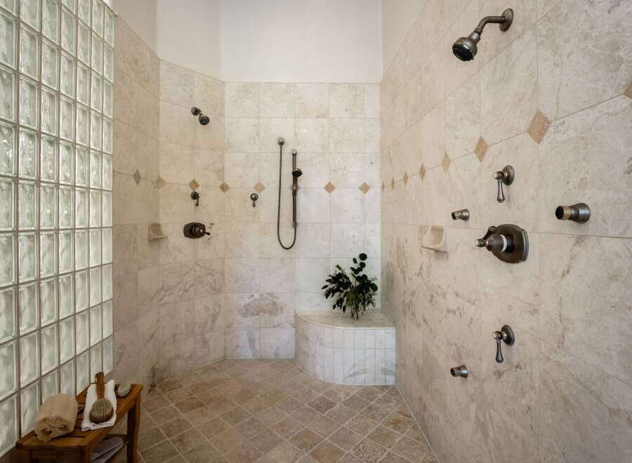 Experience ultimate relaxation in this luxurious spa-like shower featuring multiple shower heads and a built-in bench.