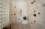 Experience ultimate relaxation in this luxurious spa-like shower featuring multiple shower heads and a built-in bench.