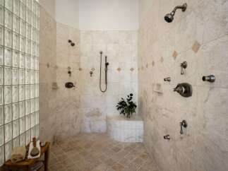 Experience ultimate relaxation in this luxurious spa-like shower featuring multiple shower heads and a built-in bench.
