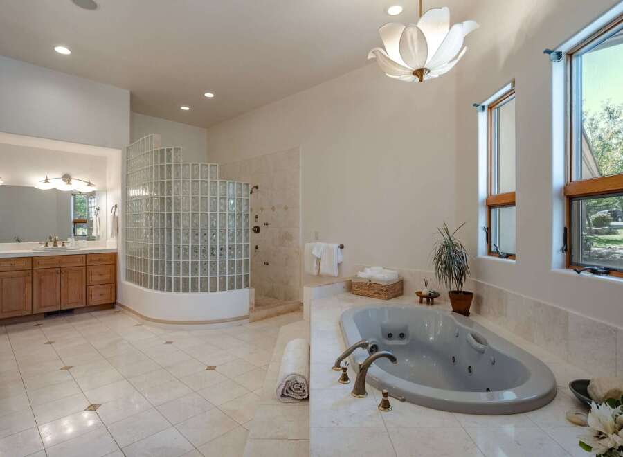 Indulge in luxury in this spacious master bathroom, featuring a large soaking tub and a separate glass-block shower enclosure.