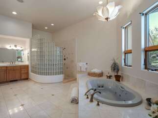 Indulge in luxury in this spacious master bathroom, featuring a large soaking tub and a separate glass-block shower enclosure.