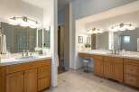 This spacious bathroom features dual vanities with ample counter space and warm wooden cabinetry, perfect for a master suite.