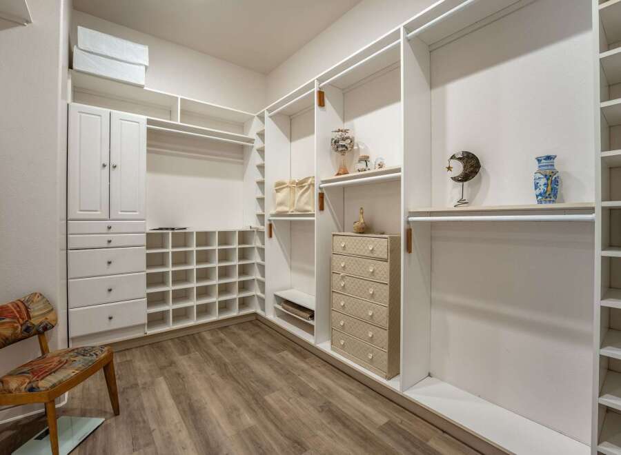 Discover ample storage in this spacious walk-in closet, featuring custom white shelving and cabinetry.