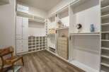 Discover ample storage in this spacious walk-in closet, featuring custom white shelving and cabinetry.