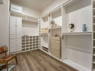 Discover ample storage in this spacious walk-in closet, featuring custom white shelving and cabinetry.