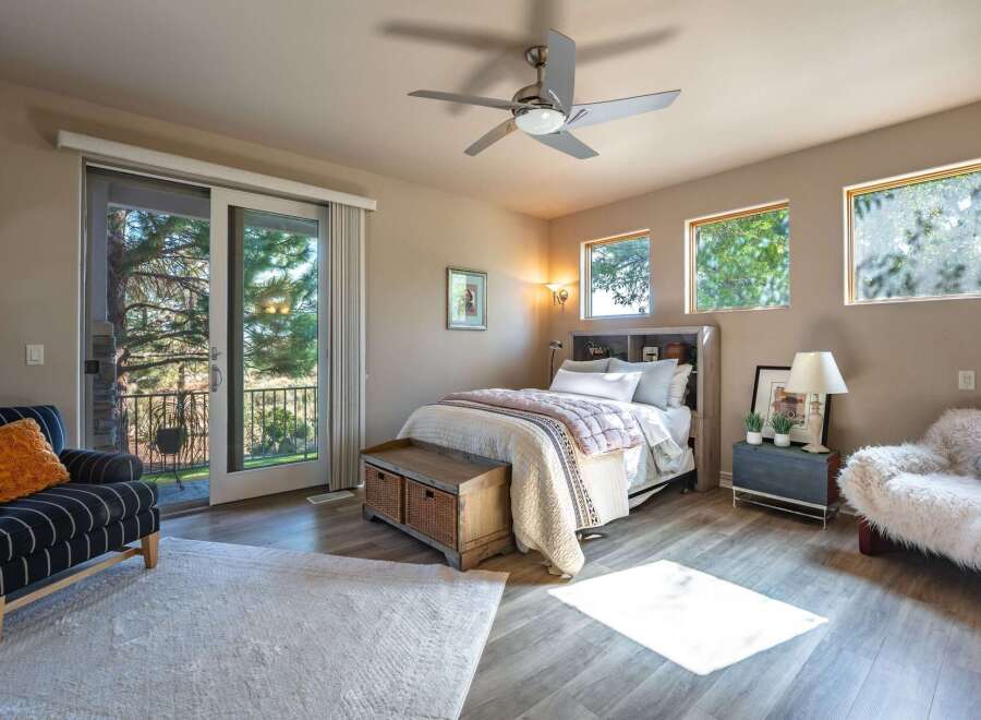 Experience serene living in this charming bedroom featuring a comfortable bed, a rustic wooden storage bench, and a cozy armchair.
