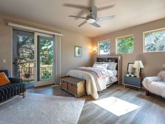 Experience serene living in this charming bedroom featuring a comfortable bed, a rustic wooden storage bench, and a cozy armchair.