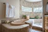 Indulge in relaxation in this luxurious bathroom featuring a spacious corner bathtub with a tiled surround and a separate shower area.