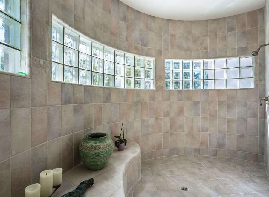 Experience luxury and natural light in this stunning bathroom featuring a curved shower with frosted glass block windows.