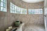 Experience luxury and natural light in this stunning bathroom featuring a curved shower with frosted glass block windows.