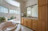 Indulge in relaxation in this luxurious bathroom featuring a spacious, curved soaking tub and a separate shower area.