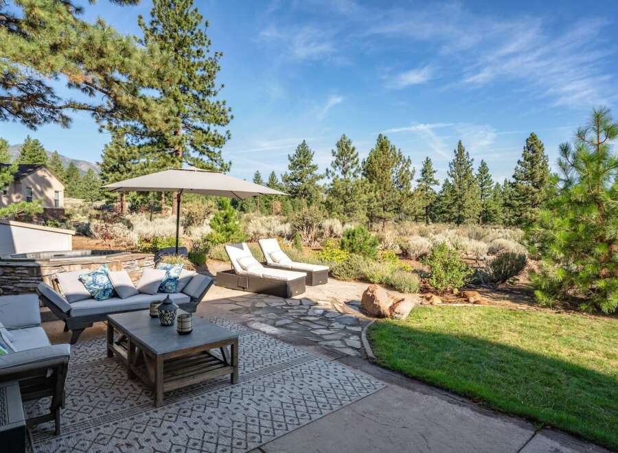 Enjoy outdoor living at its finest with this stunning patio featuring comfortable seating, chaise lounges, and a large umbrella for shade.