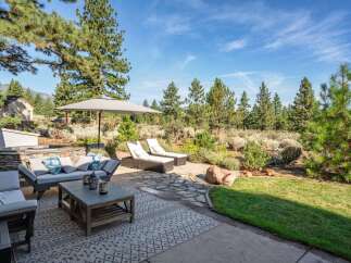 Enjoy outdoor living at its finest with this stunning patio featuring comfortable seating, chaise lounges, and a large umbrella for shade.