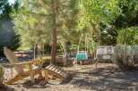 Enjoy the outdoors in this charming garden space featuring comfortable Adirondack chairs and a unique wooden footrest, perfect for relaxing.