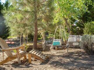 Enjoy the outdoors in this charming garden space featuring comfortable Adirondack chairs and a unique wooden footrest, perfect for relaxing.