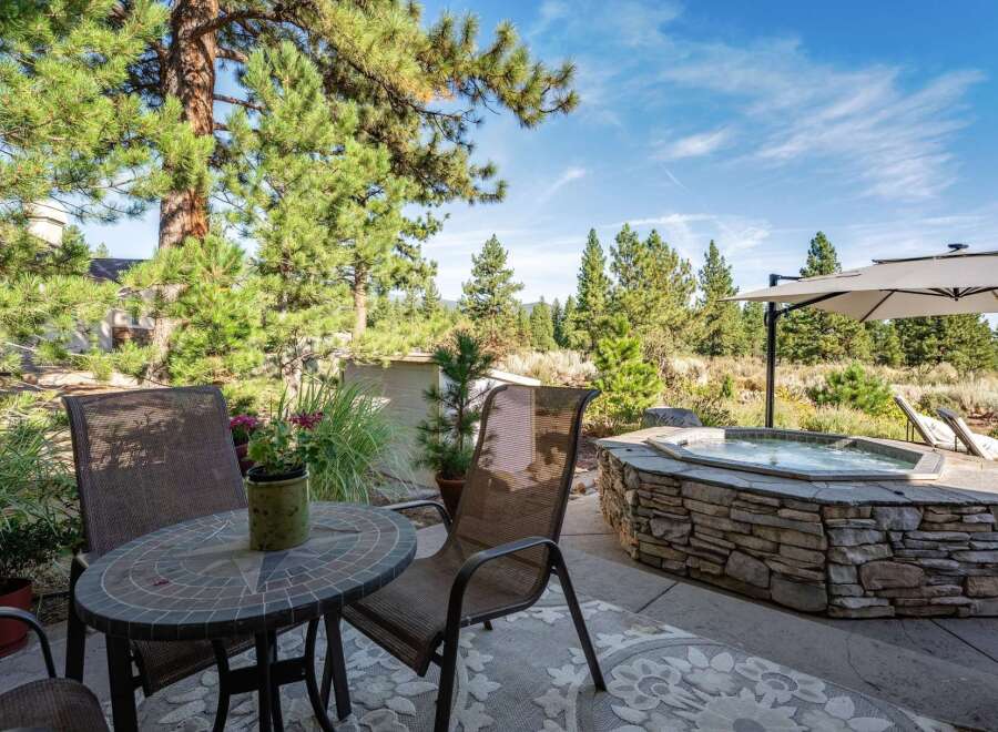 Enjoy outdoor living at its finest with this stunning patio featuring a luxurious stone-encased hot tub, perfect for relaxation.