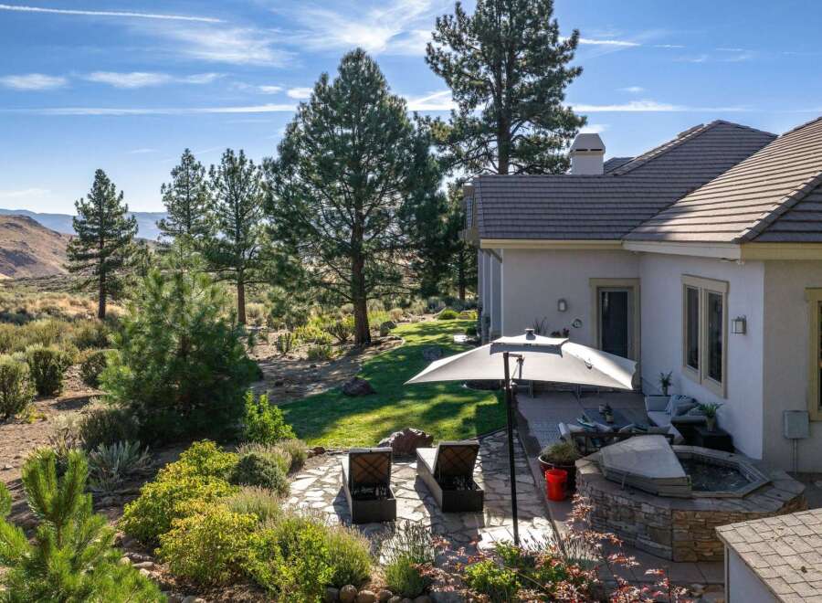 Experience luxurious outdoor living with this stunning backyard oasis, featuring a relaxing hot tub and comfortable lounge chairs perfect for soaking up the sun.