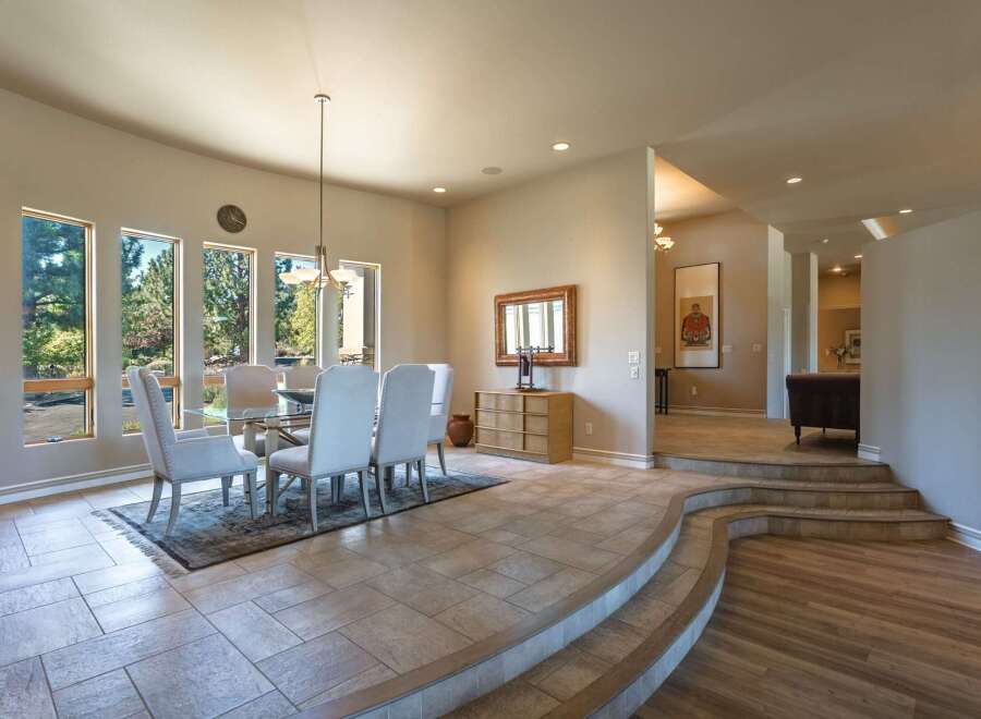 Experience elegant dining in this spacious room featuring a glass-top dining table with upholstered chairs, perfect for hosting gatherings.