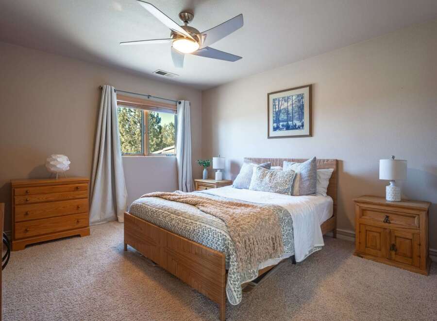 Experience comfort and style in this inviting bedroom, featuring a plush queen-size bed adorned with decorative pillows and a cozy throw blanket.