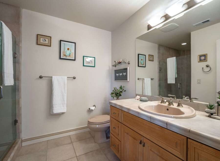 This bright and airy bathroom features a spacious vanity with a light pink sink and ample counter space, perfect for your morning routine.