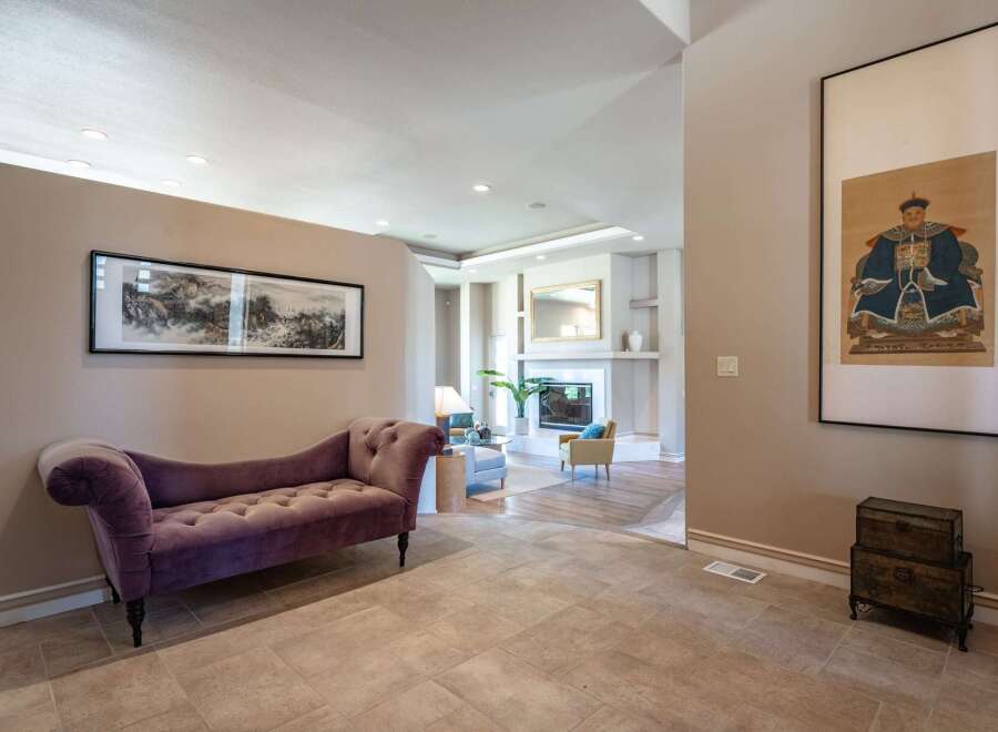 Step into this elegant entryway featuring a plush purple chaise lounge perfect for a moment of relaxation.