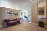 Step into this elegant entryway featuring a plush purple chaise lounge perfect for a moment of relaxation.