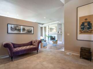 Step into this elegant entryway featuring a plush purple chaise lounge perfect for a moment of relaxation.