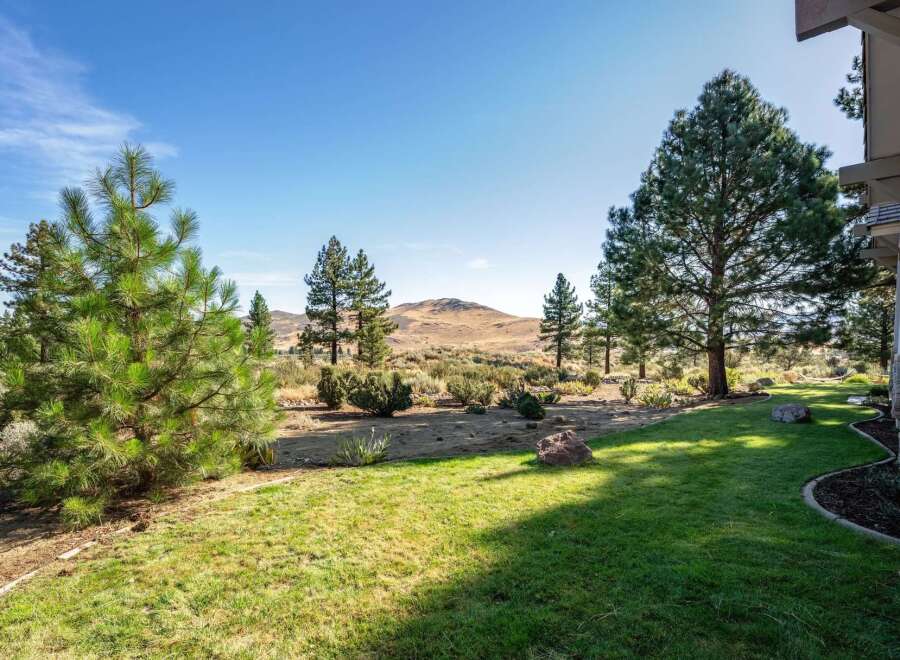 Experience the serene beauty of this property, featuring a lush green lawn that seamlessly transitions into a natural landscape.