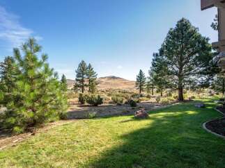 Experience the serene beauty of this property, featuring a lush green lawn that seamlessly transitions into a natural landscape.