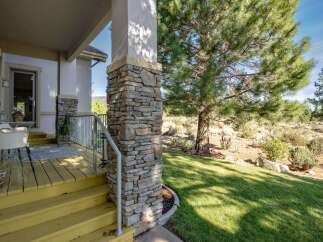 Welcome guests onto a charming yellow-painted porch with a stone-accented pillar, perfect for enjoying the serene natural surroundings.